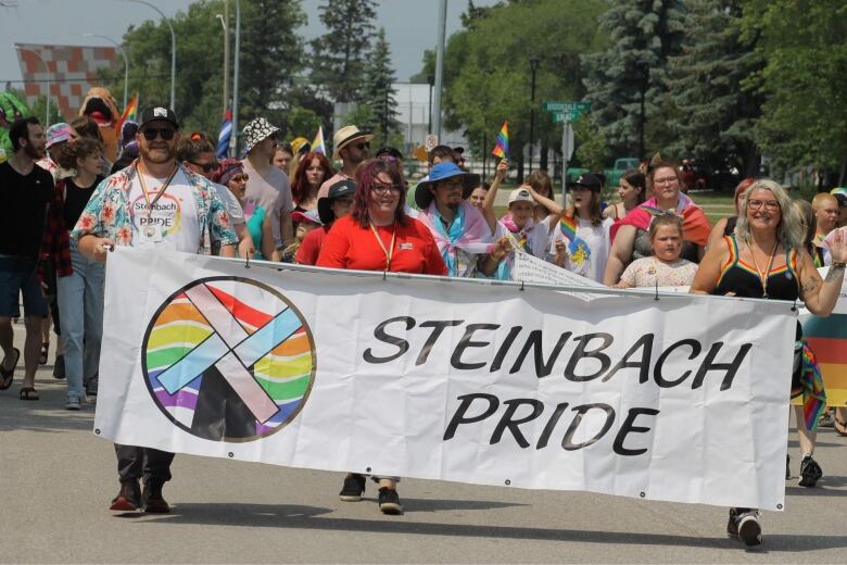 People holding a sign that says Steinbach Pride