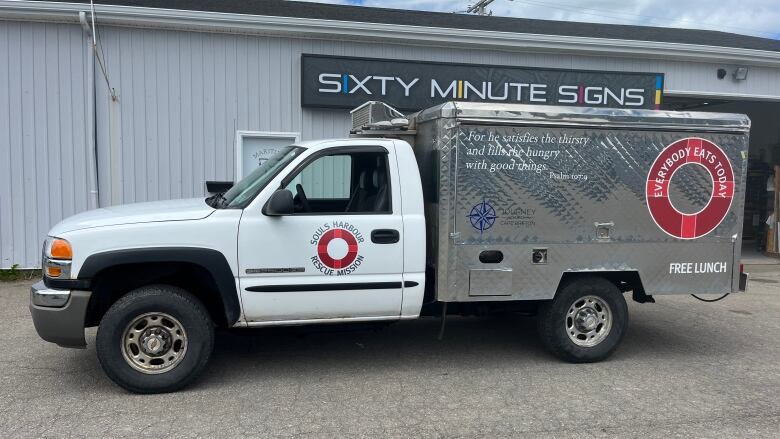 A food truck is seen parked in front of a garage.