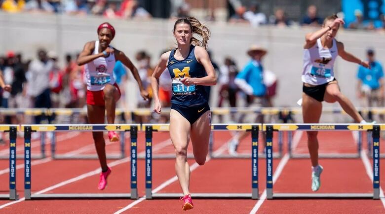 A female hurdler is seen racing.