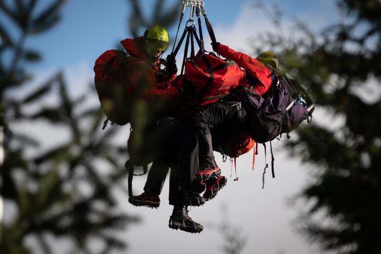 North Shore Search and Rescue team hang from a helicopter, allegedly with a snowshoer who had gone missing the night before, as it arrives at a helicopter base in North Vancouver