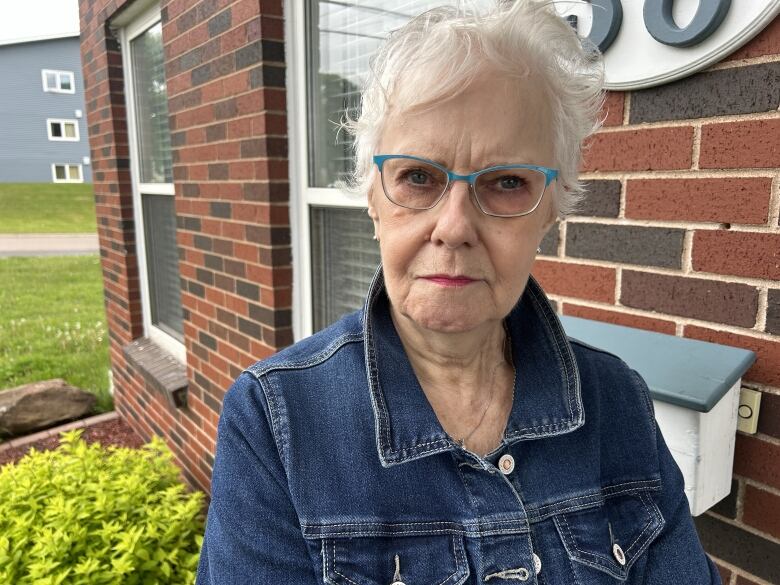 Woman with white hair wearing blue jean jacket.