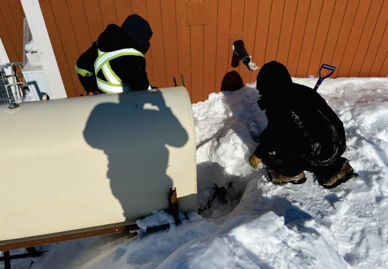 Two people dig through snow.