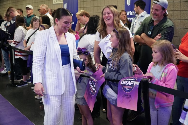 A person smiling while talking to young hockey fans.