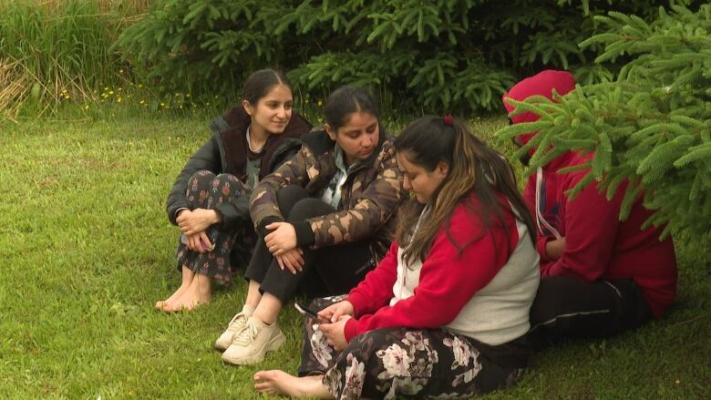 Four people sitting on the grass.