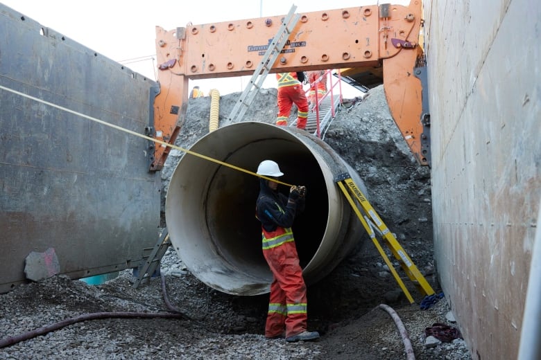 a man stands by a large exposed pipe