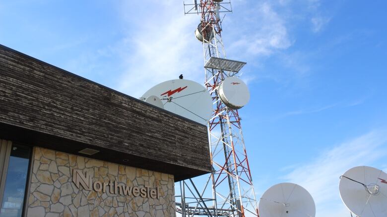 Brown building with satellite dishes on tower against blue sky.