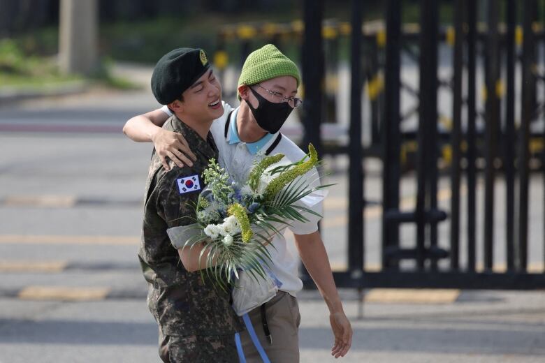 Jin, in uniform, is seeing being greeted by BTS member J-Hope, after Jin was discharged from the military on Wednesday after serving his mandatory time in the army.