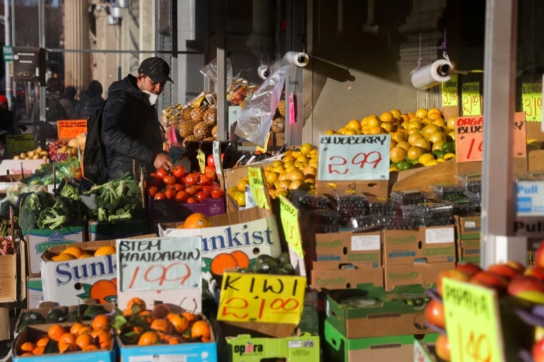 A man looks through fresh produce displayed outside a grocery store.