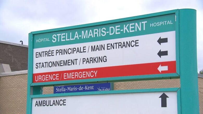 A large bilingual sign for Stella-Maris-de-Kent Hospital in front of a beige brick building.