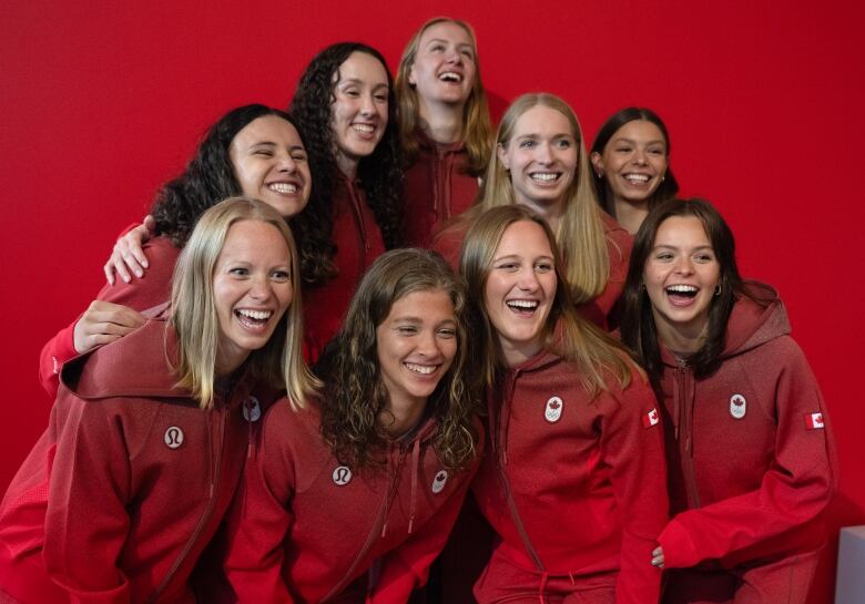 9 women wearing red Team Canada jackets and smiling 