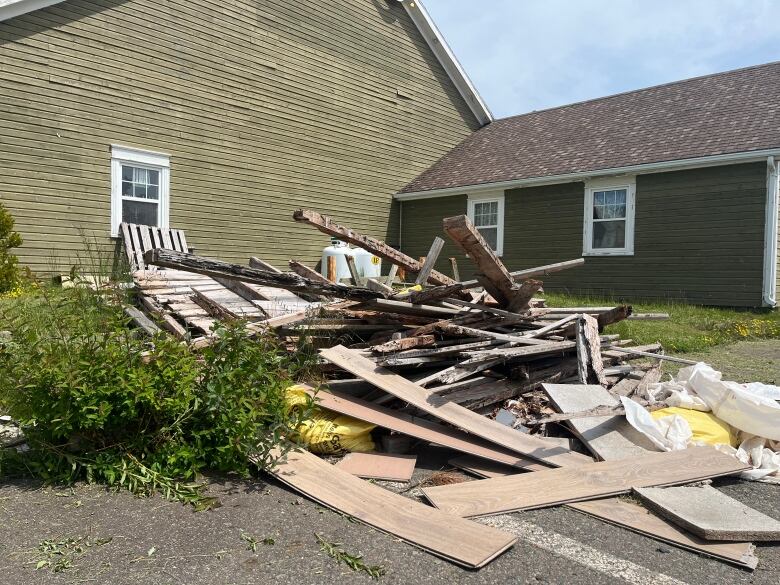 A pile of wood sits on the edge of a parking lot next to a gift shop.