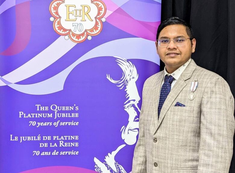 Madhurja Ghosh stands next to a purple poster. 