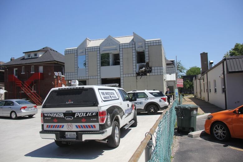 A police car in front of a building with fire damage