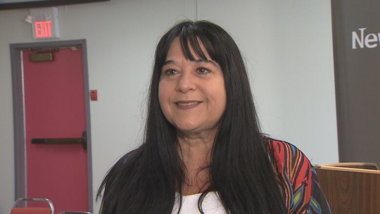 Woman with black hair and bangs smiles at camera.