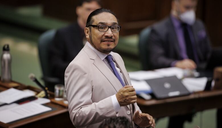 A person wearing a suit stands in a room.