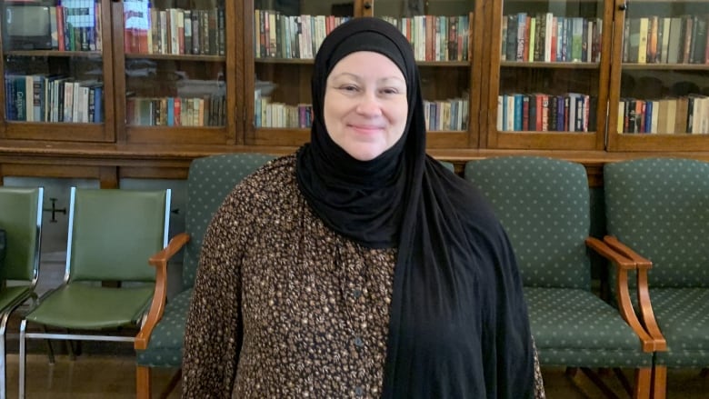 Woman wearing hijab with back to bookcase. 