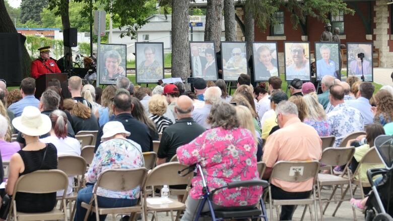 A row of portaits are seen standing outside in front of a crowd.