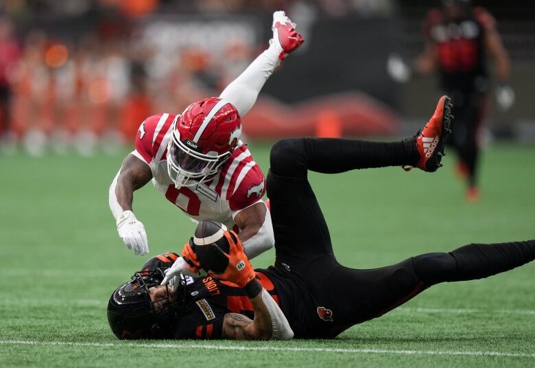 two men in football uniforms jump through the ait