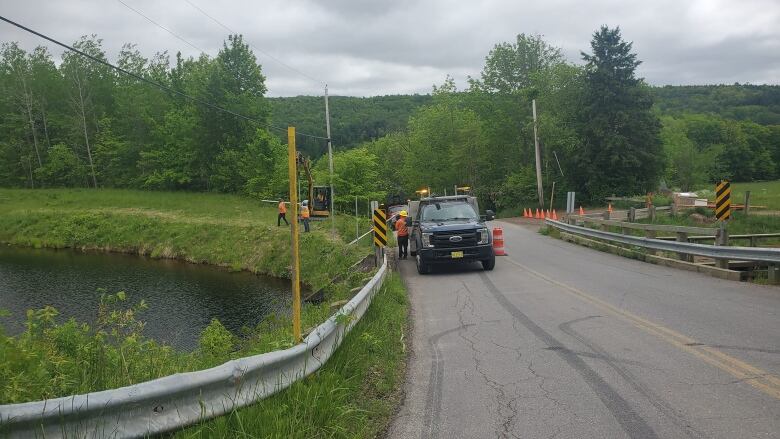 a truck stopped on a bridge to conduct construction work along a body of water. 