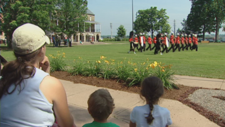 Tourists watch the changing of the guard in Officers' Square on a sunny day.