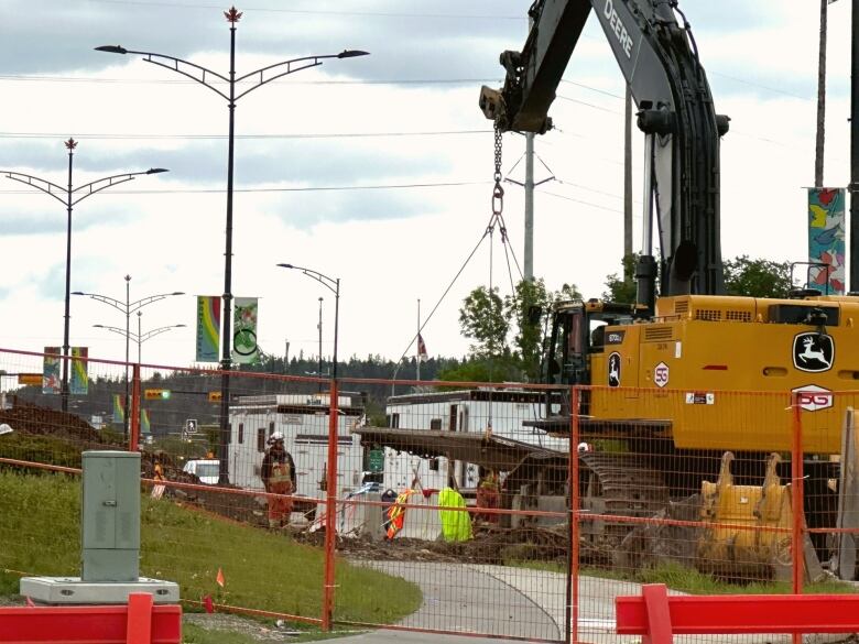 A bulldozer stands behind a construction fence. 