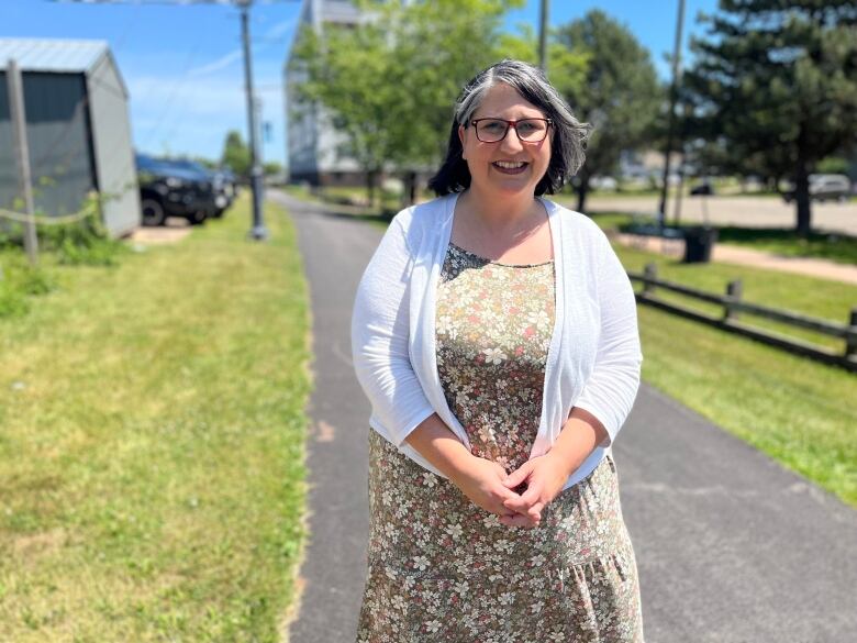 A woman in a dress and a cardigan smiles.