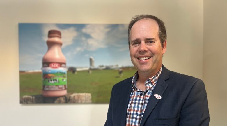 Man standing in front of photo of chocolate milk.