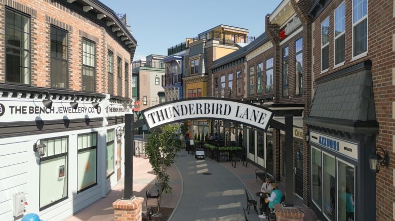 A sign called Thunderbird Lane is shown with brick buildings, local cafes and restaurants in the back. 