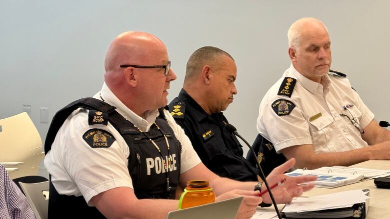 Unformed police officers present at a table with papers and a lap top 