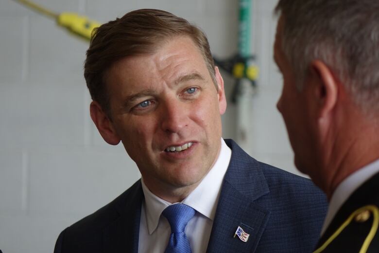 A man wearing a suit speaks with a firefighter.