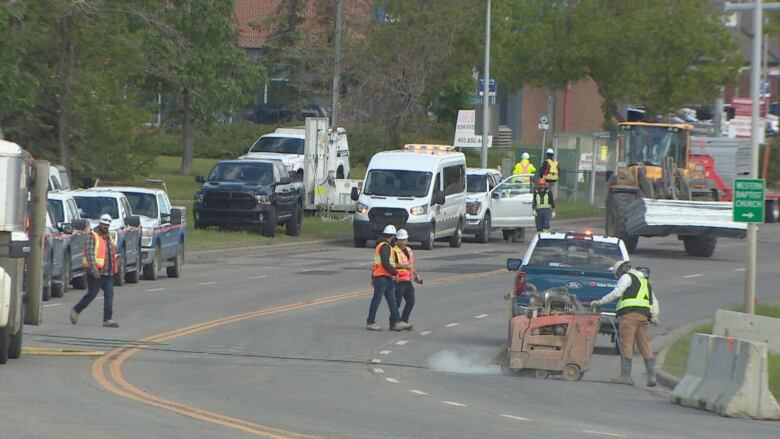 work crews operate construction equipment on a road.