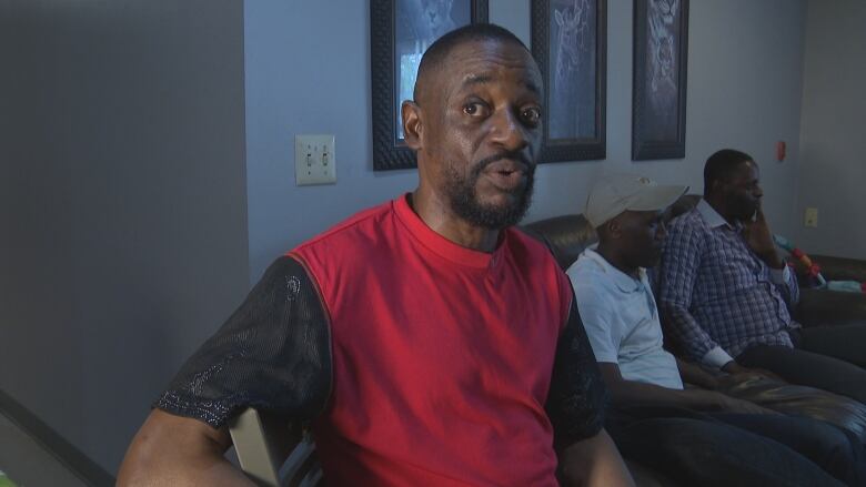 A man in a red shirt speaks to the camera