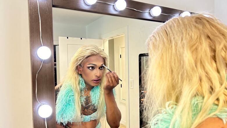 A South Asian man dressing up in drag in front of mirror.