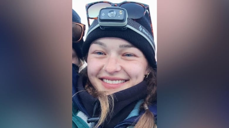 A white woman wearing a GoPro and a beanie smiles.