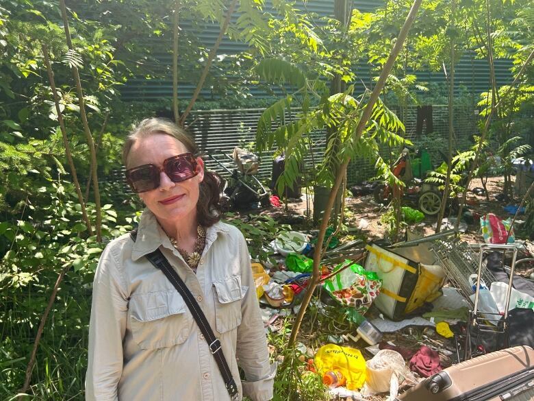 Judson Street resident Sarah Giles stands by a pile of garbage across the street from homes on the quiet street. The garbage has been associated by neighbours with a nearby homeless encampment in a park at 10 Judson.