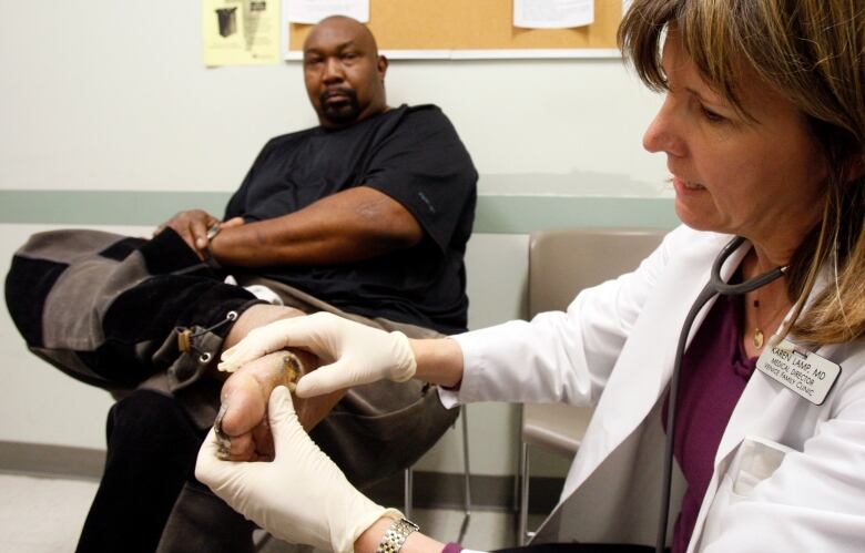 A female doctor, right, examines a diabetic ulcer on the foot of a man at a clinic.