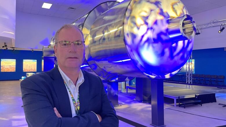 Man stands next to a cylinder model of a nuclear reactor. 