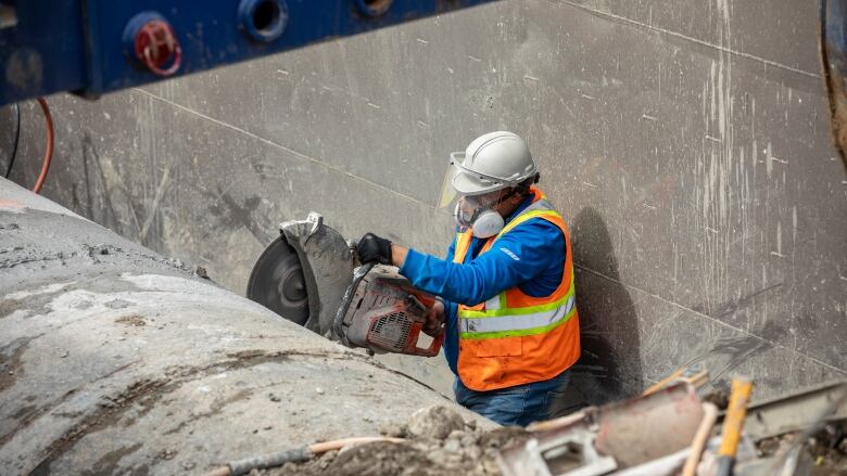 a construction worker saws a giant pipe.