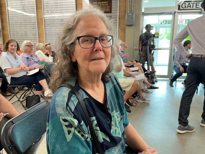 A woman with grey hair wearing glasses.