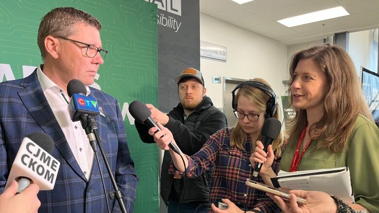 A man takes questions from several reporters.