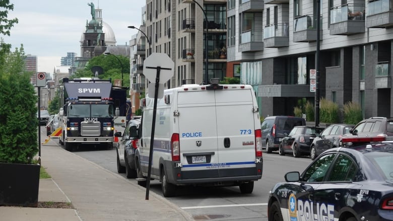 Police vehicles on street near apartment buildings.