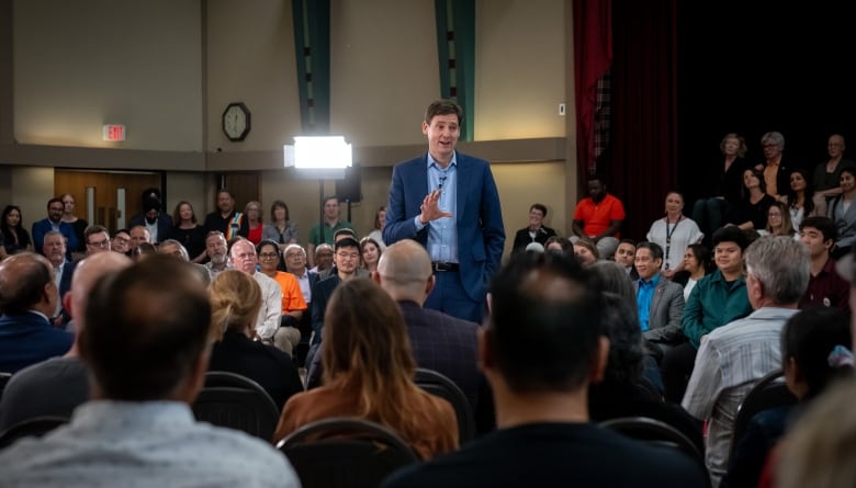 A man in a blue suit speaks to a crowd