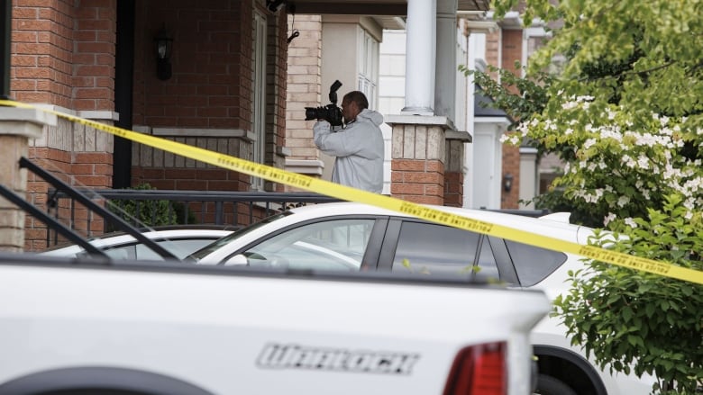 Police and bystanders are pictured at the scene of a shooting.