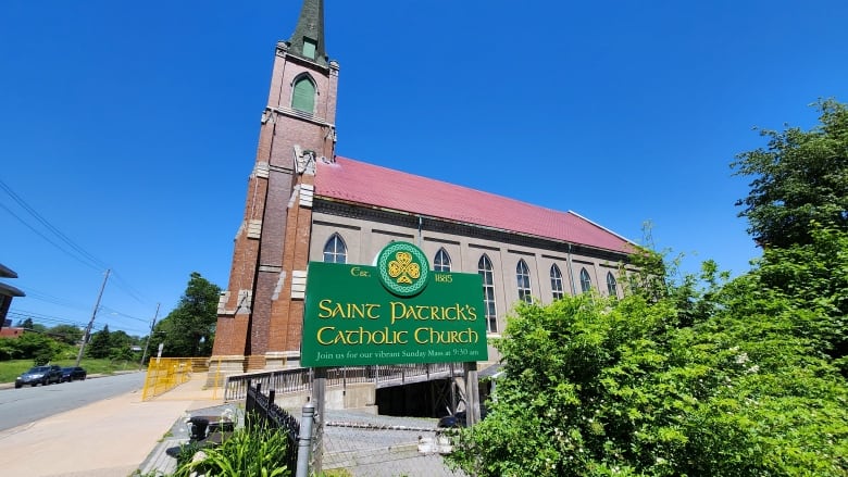 A Victorian gothic brick church with a steeple and a sign saying St. Patrick's Catholic Church.