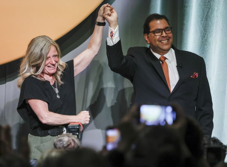 Notley and Nenshi hold their hands in the air.