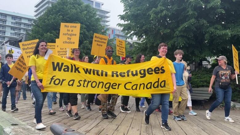 a group of people wlak with signs supporting refugees 