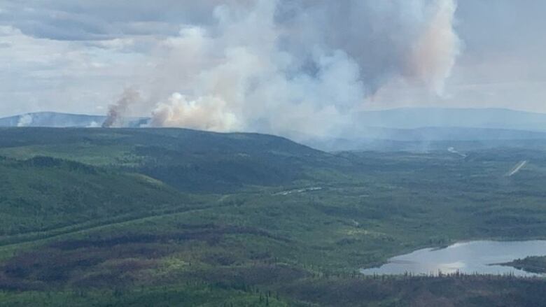 An aerial view of a remote landscape, with wildfire smoke visible in the distance.