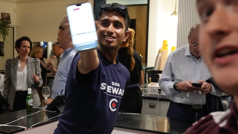 A campaign workers holds a mobile phone up to the camera showing election results in Don Steward's election headquarters. 