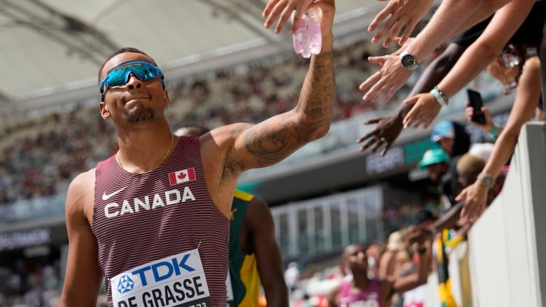 Canadian male sprinter receives high fives from fans during the men's 200-meter heat at the World Athletics Championships in Budapest, Hungary, Wednesday, Aug. 23, 2023. (AP Photo/Ashley Landis)