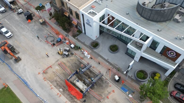 an aerial view of an open excavation showing a large pipe and multiple construction workers.